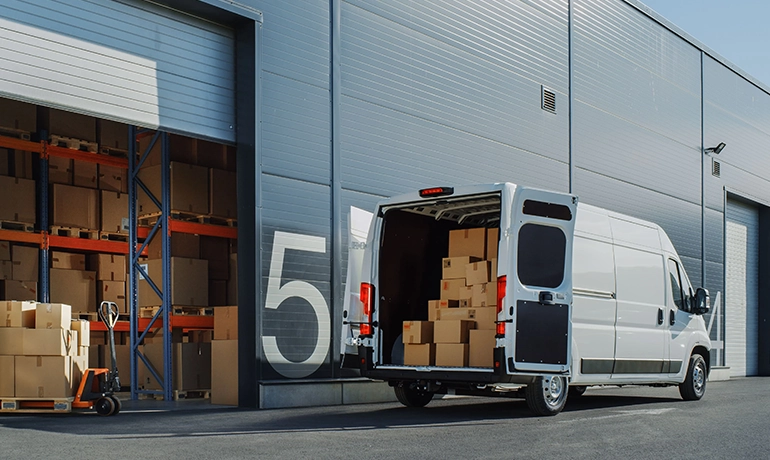 Last Mile Delivery Challenges & Growth in Rural India Delivery van unloading packages at warehouse for last mile logistics services in rural India